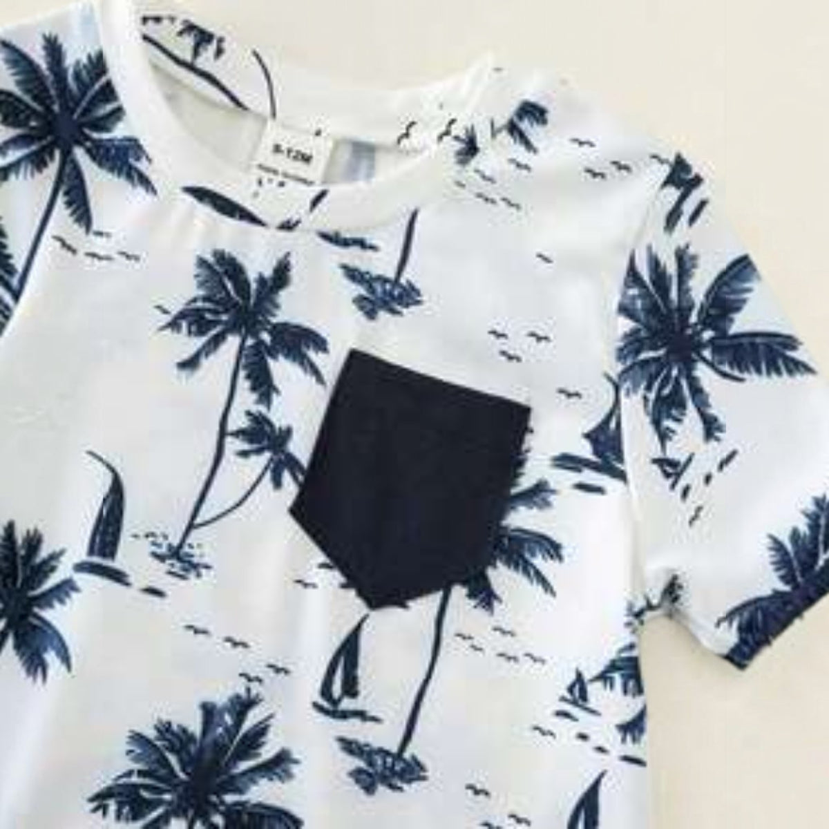 Babylove Nauru baby boy white t-shirt with navy blue coconut tree print, short sleeves, and a solid navy chest pocket